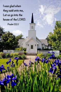 a white church with blue flowers in the foreground and a bible verse written on it