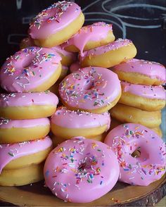 a pile of doughnuts with pink frosting and sprinkles on them