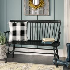 a black bench sitting in front of a painting on the wall next to a window