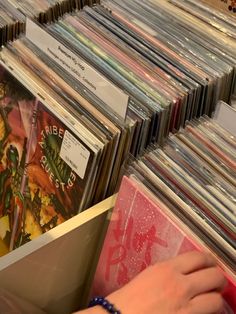 a person's hand is picking up cds from a shelf in a record store