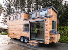 a tiny house on wheels parked in front of some trees