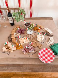 a wooden table topped with lots of different types of cheese and crackers next to a bottle of wine