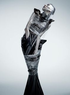 a woman is wrapped in plastic and posing for the camera