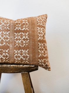 a brown and white pillow sitting on top of a wooden stool