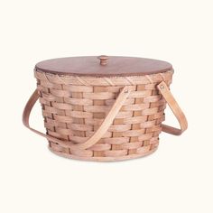 a woven basket with leather straps on the front and side, sitting against a white background