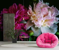 a pink chair sitting on top of a white table next to a vase filled with flowers