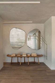 two circular mirrors hanging on the wall in a room with wooden benches and tables below them