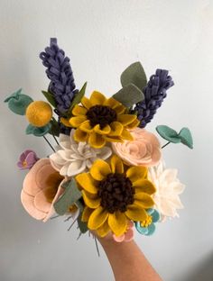 a hand holding a bouquet of flowers made out of felt