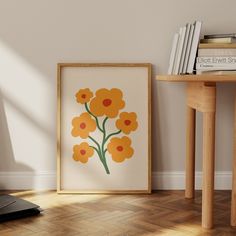 an orange and yellow flower is on display in front of a white wall next to a wooden table