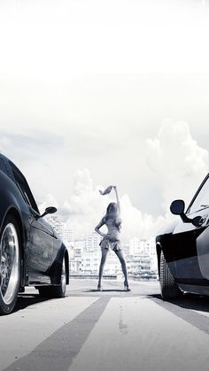 two cars parked next to each other in front of a woman standing on the side of the road