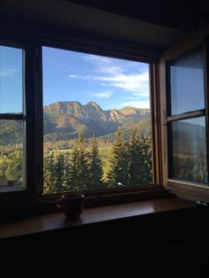 a window with mountains in the background and a bowl sitting on a ledge next to it