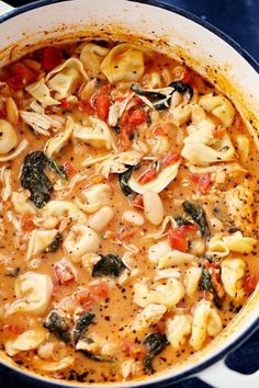 pasta and spinach soup in a pot on a blue tablecloth with utensils