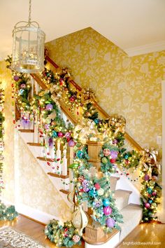 a staircase decorated with christmas decorations and garland on the bannister, next to a chandelier