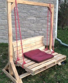 a swing bed made out of pallet wood with a pillow on it and rope