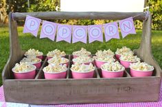 a wooden box filled with cupcakes on top of a pink and white checkered table