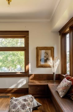 a wooden bench sitting in front of a window next to a pillow on the floor