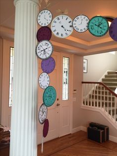 a bunch of clocks hanging from the side of a wall next to a stair case