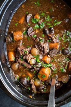 a bowl filled with stew and carrots on top of a table