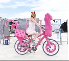 a woman in a pink dress is riding a pink bike with a flamingo decoration on it