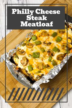 a cheesy steak meatloaf in foil on a cutting board