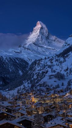 the mountain is covered in snow and lit up by street lights at night with buildings below