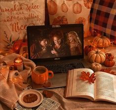 an open laptop computer sitting on top of a table next to pumpkins and candles