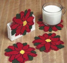 three red poinsettia coasters and a glass of milk on a table