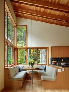 a living room filled with furniture next to a kitchen and dining table in front of large windows