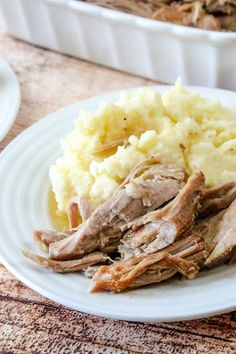 a white plate topped with meat and mashed potatoes next to a casserole dish