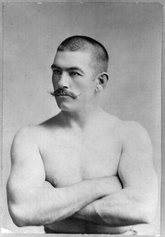 an old photo of a shirtless man with his arms crossed