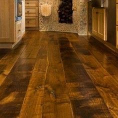 a wood floor in a kitchen with an oven and counter top on one side and cabinets on the other