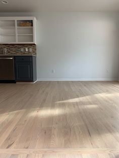 an empty living room with hard wood flooring and white painted walls in the background