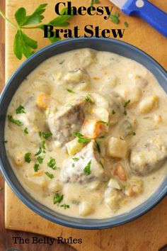 a bowl of cheesey brat stew on a cutting board