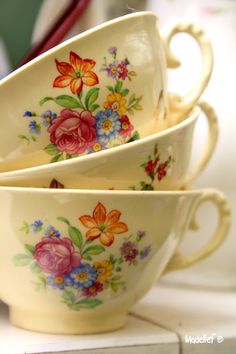 three bowls with flowers painted on them sitting next to each other in front of a mirror