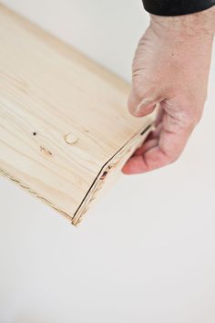 a person holding a piece of wood with one hand and another hand on top of it