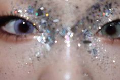 a woman's face with glitter on it and her eyes are half covered by silver flecks