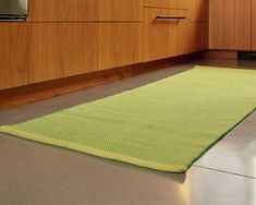 a kitchen area with wooden cabinets and green rugs on the floor in front of an oven