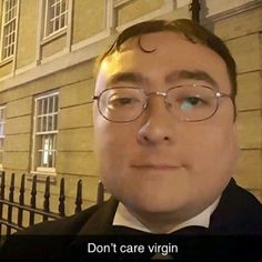 a man wearing glasses and a bow tie standing in front of a building with the words don't care virgin on it