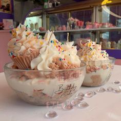 three cupcakes with white frosting and sprinkles in a bowl