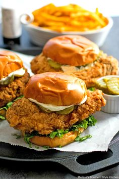 fried chicken sandwiches with pickles and coleslaw on a tray next to french fries