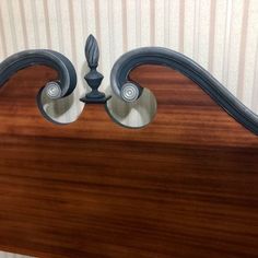 a wooden headboard with two metal finials on it's sides and an ornate design at the top