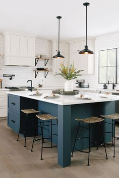 a kitchen island with two stools next to it and lights hanging from the ceiling