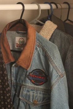 a denim jacket with patches on it and a tie hanging from the rack next to it