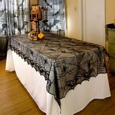 the table is covered with black lace and has pumpkins on it, along with other decorations