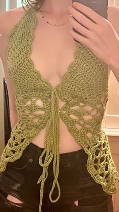 a woman taking a selfie with her cell phone wearing a green crochet top