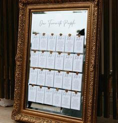 a gold framed mirror sitting on top of a floor next to a table with place cards in it