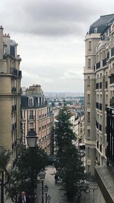 an alley way in the middle of a city with tall buildings on both sides and people walking down it