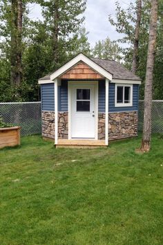 a small blue and white shed sitting in the grass