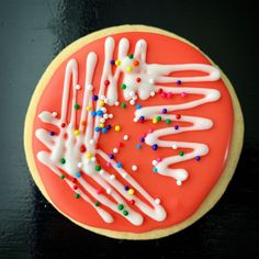 a cookie decorated with white icing and sprinkles on a black surface