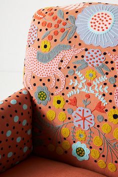 an upholstered chair with colorful flowers and dots on the backrest is seen in this image